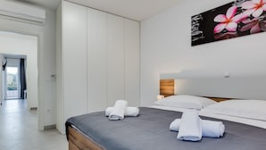 A modern bedroom with a large bed, a wooden headboard, and a painting of flowers on the wall.