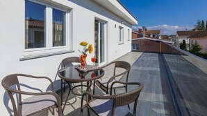 Un edificio moderno con balcón, con mobiliario de mimbre y una mesa de vidrio.
