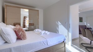Un dormitorio moderno con una cama grande, un espejo y vistas a una sala de estar.