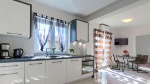 Una cocina moderna con armarios blancos, horno integrado y cafetera.