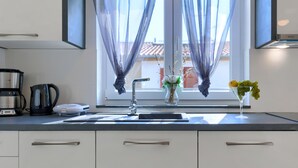 Una cocina moderna con un lavamanos, una cafetera, un hervidor y un florero con flores.