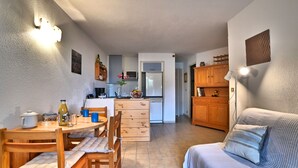 A compact living space with a dining area, kitchenette, and a sofa. - l'Oasis by Interhome (Ile d'Oléron)