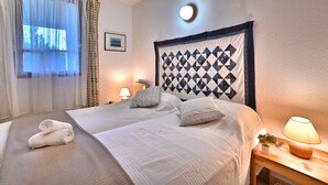 A hotel room with a bed, a bedside lamp, a window with sheer curtains, and a wall-mounted light fixture. - l'Oasis by Interhome (Ile d'Oléron)