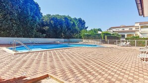 A swimming pool with a brick deck, surrounded by lounge chairs and a clear view of trees and buildings in the background. - l'Oasis by Interhome (Ile d'Oléron)