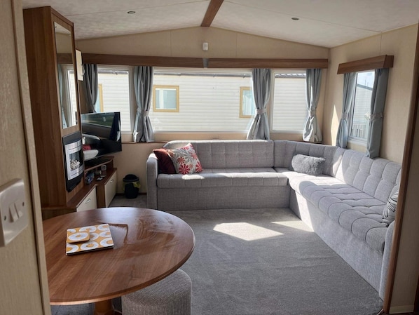 A cozy RV interior with a sofa, a TV, and a dining table.