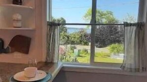 Eine Küche mit großem Fenster, einem Esstisch mit Tellern und einem Steinboden.