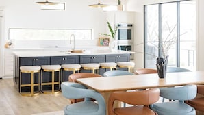 Una cocina amplia con una isla grande, vigas de madera e iluminación colgante.