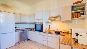 A modern kitchen with white cabinets, a dishwasher, an oven, and a wooden countertop. - Blooming Villa Cos with Garden and Lake View, Belgirate, Italy (Belgirate)