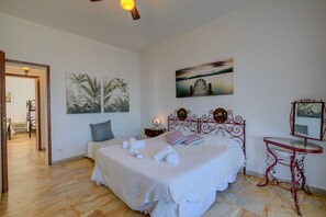 Quarto com cama, mesa de cabeceira, espelho e obras de arte nas paredes.