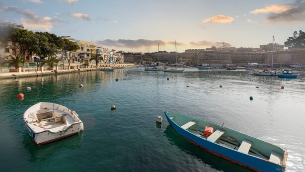 A harbor with boats, a fort, and buildings along the waterfront.