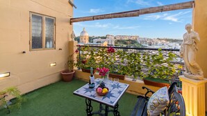 A balcony with a table, potted plants, and a statue.