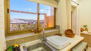 A kitchen with a window, a sink, and a countertop with bowls and a fruit bowl.