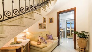 A living room with a sofa, a table with a candle, and a staircase.