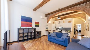 A modern living room with a wooden floor, a blue sofa, and a TV. - Charming Apartment Next To Genoa's Aquarium, Genova, Italy (Genova)