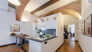 A modern kitchen with a central island, white cabinetry, and a brick archway. - Charming Apartment Next To Genoa's Aquarium, Genova, Italy (Genova)