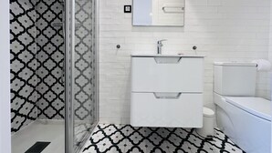 Une salle de bain équipée d’une douche, d’un lavabo, de toilettes et d’un miroir.