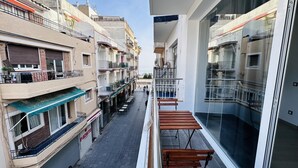 Un immeuble de grande hauteur doté de nombreux balcons, d’un espace extérieur aménagé pour s’asseoir et offrant une vue sur la rue.