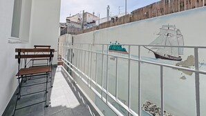 En balkon med træbænk, gelænder af glas og et muralmaleri af en sejlbåd.