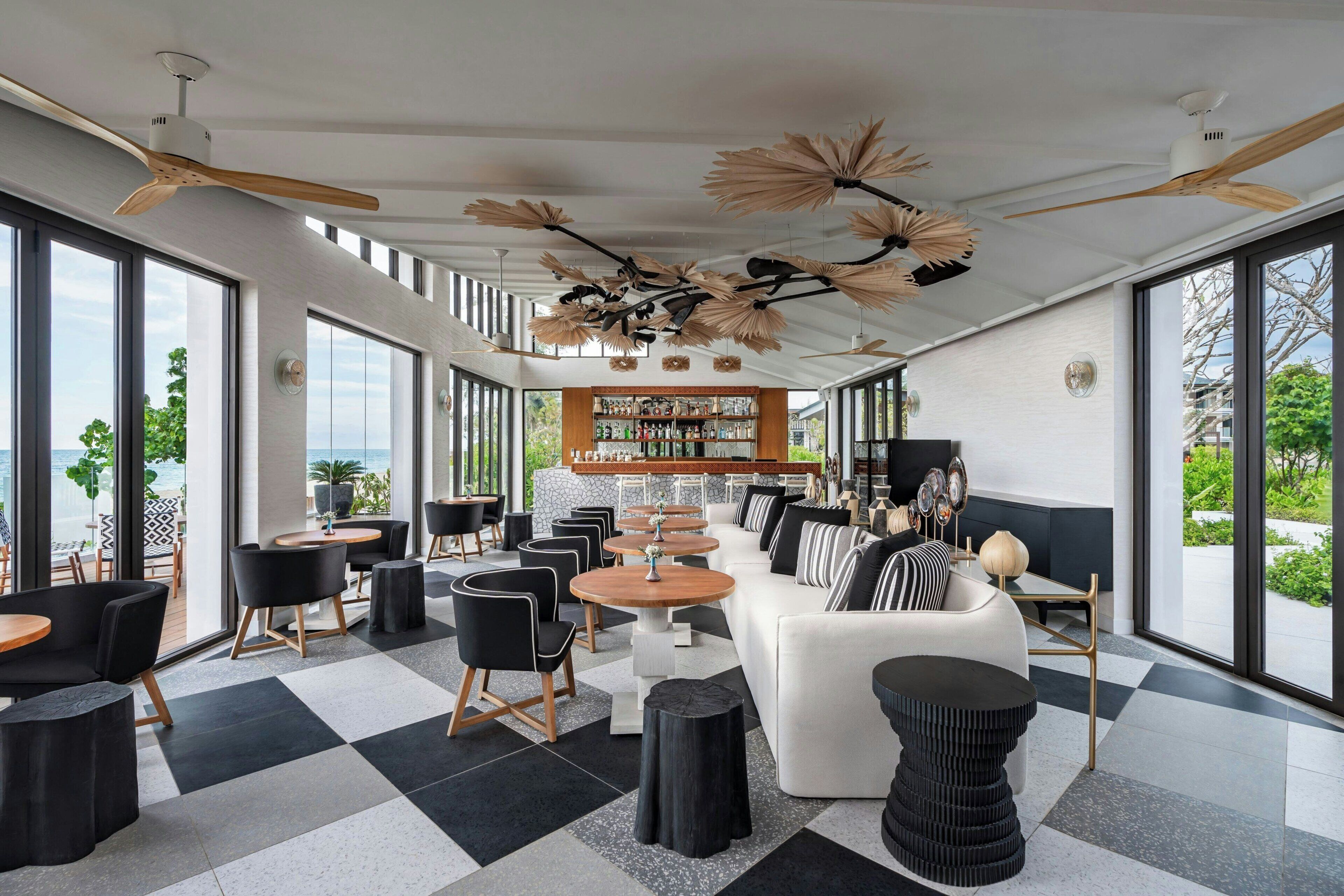 Un interior moderno con piso a cuadros, una zona de bar y amplias ventanas que ofrecen vistas al exterior.