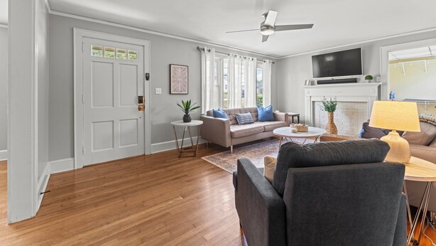 A living room with a sofa, a coffee table, a TV, and a ceiling fan.
