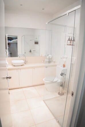 A modern bathroom with a glass shower enclosure, a white sink, and a toilet. - The White House-Studio (Metung)