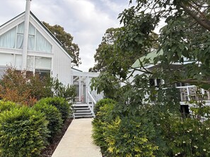 A white building with large windows and a covered walkway leading to a staircase. - The White House-Studio (Metung)