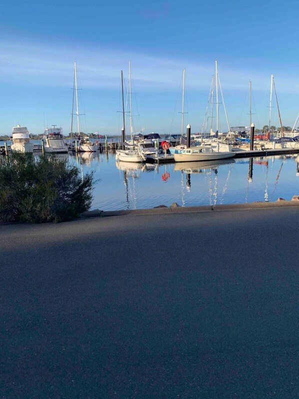 En lysthavn med flere sejlbåde i havn, roligt vand og en klar himmel.
