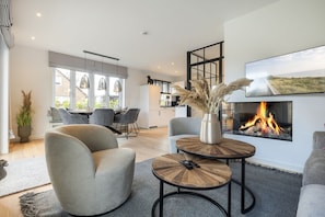 Una sala de estar moderna con chimenea, asientos cómodos y zona de comedor.