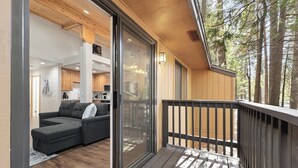 Interior moderno com deck de madeira, porta de correr de vidro que dá para uma sala de estar e vista para uma área arborizada.