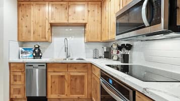 Een moderne keuken met houten kastjes, roestvrijstalen apparatuur en een witte betegelde achterwand.