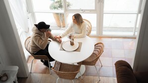 Un coin repas avec une table ronde, des chaises en osier et une plante en pot.