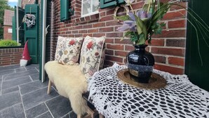 Un rincón exterior acogedor con una mesa, un jarrón decorativo y una estatua de gnomo.