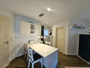 A compact kitchen with a central island, white cabinetry, and a hanging light fixture.