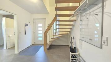 A modern interior with a wooden staircase, a hallway, and a wall-mounted drying rack.
