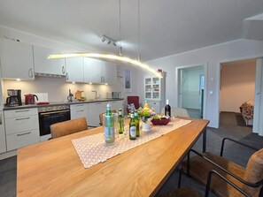 Una cucina moderna con mobili bianchi, un tavolo da pranzo in legno e un'isola.