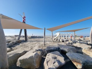 A beach with large rocks, a lifeguard tower, and beach umbrellas.