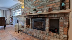 A living room with a brick fireplace, a wooden mantel, and a floor lamp.