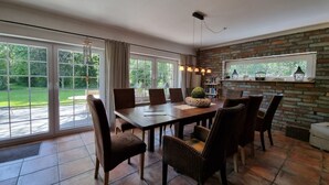 A dining area with a brick wall, large windows, and a view of a garden.