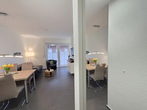 Ein modernes Wohnzimmer mit einer Couch, einem Couchtisch und einem Essbereich mit Tisch und Stühlen.