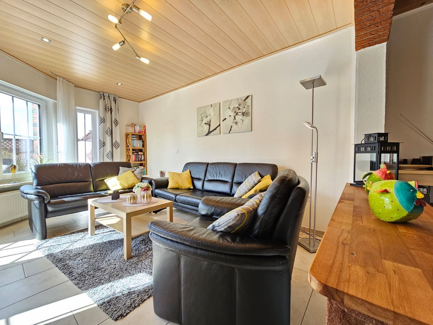 A modern living room with a leather sofa, a coffee table, and a bookshelf.