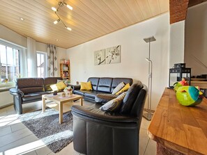 A modern living room with a leather sofa, a coffee table, and a bookshelf.