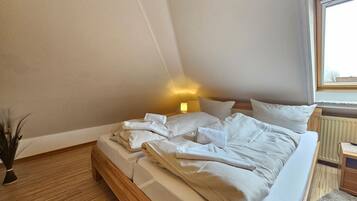 Ein Schlafzimmer mit Bett, Nachttisch, Lampe und Fenster.