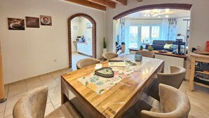 Un comedor con una mesa de madera, sillas y una cocina visible a través de un arco.