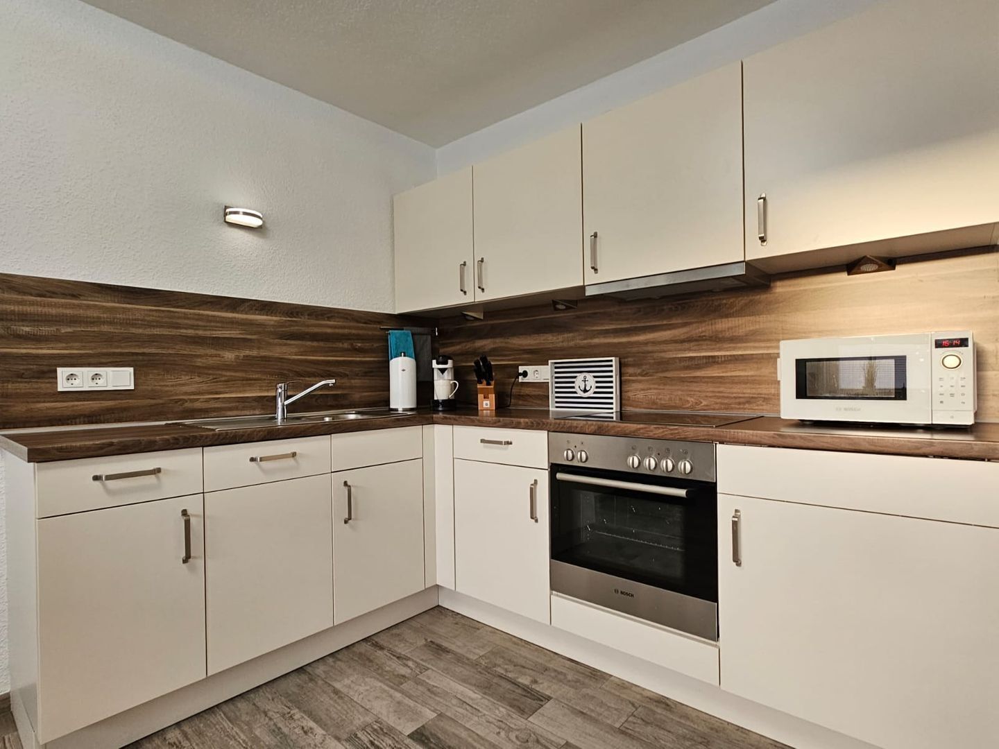A modern kitchen with white cabinets, a built-in oven, a microwave, and a coffee maker.