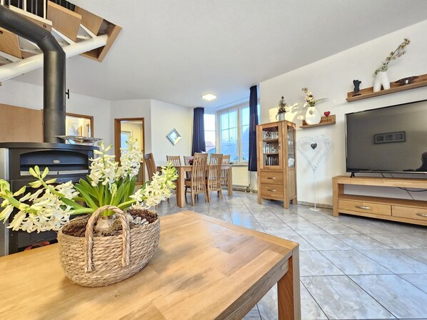 Una sala de estar moderna con chimenea, muebles de madera, televisor y comedor.