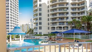 Un hotel con zona de piscina, varios balcones y vistas a otros edificios.