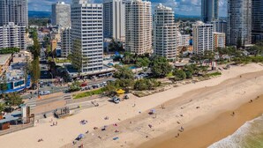 Un paisaje urbano costero con rascacielos, una playa de arena y un paseo marítimo.