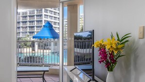Una habitación de hotel con balcón, piscina y vista a un edificio alto.
