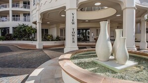 Entrada de hotel con una torre mirador, una fuente y zonas ajardinadas.