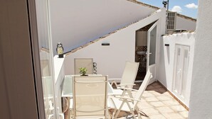 A sunlit patio with a table and chairs, a white wall, and a tiled floor. - El Palomar, in Algodonales. (Algodonales)